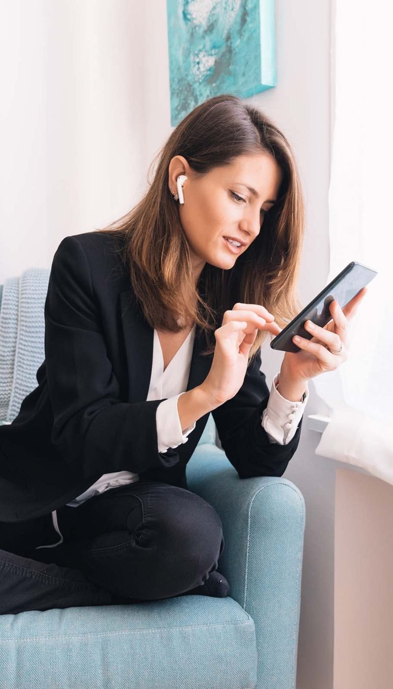 young-businesswoman-with-earphones-browsing-mobile-JE32F7L.jpg